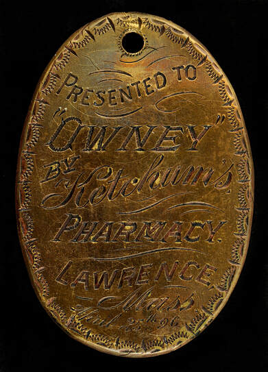 Metal dog tag that reads presented to Owney by Ketchum's Pharmacy, Lawrence, Mass.
