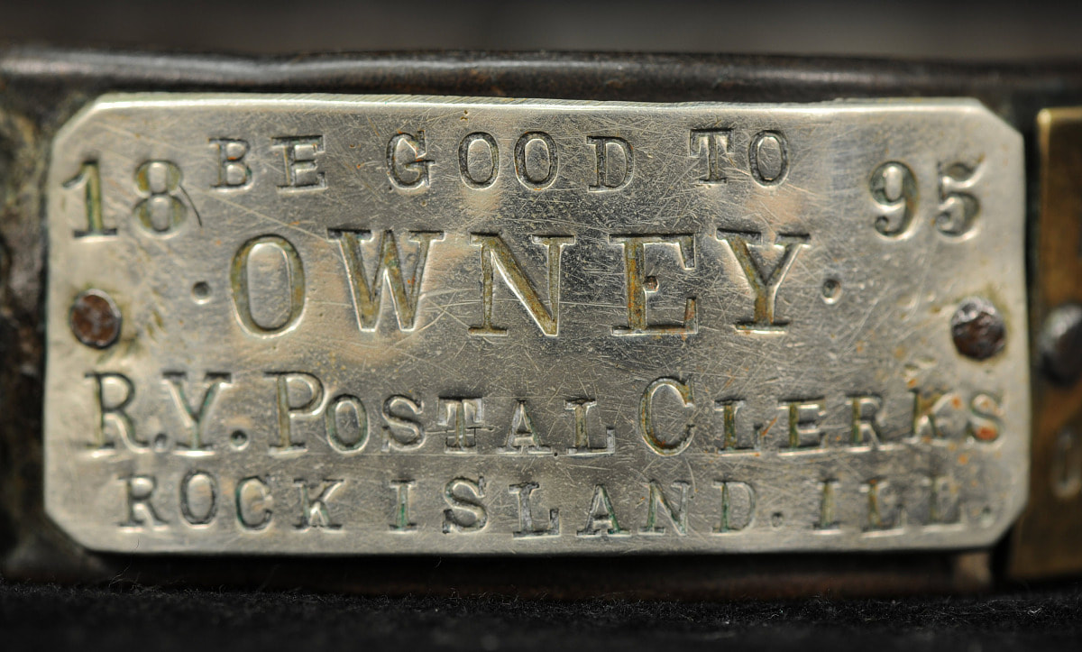 Rectangular metal tag that says Be Good to Owney