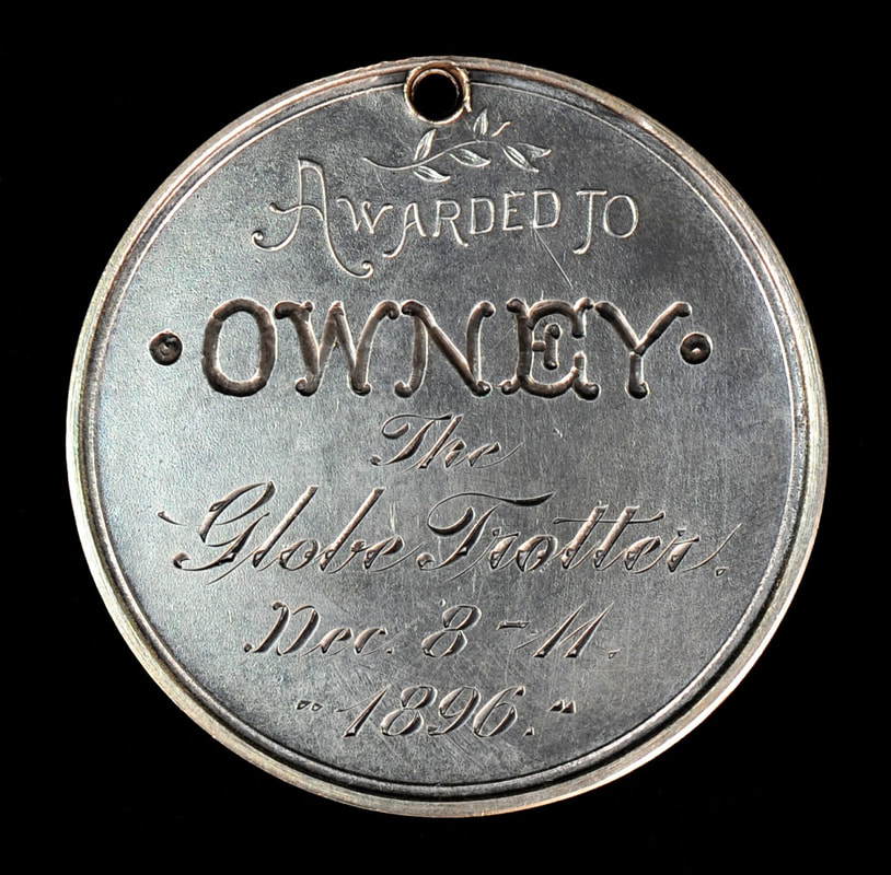 Circular metal tag that reads Awarded to Owney, the globe trotter. Dec 8-11, 1896